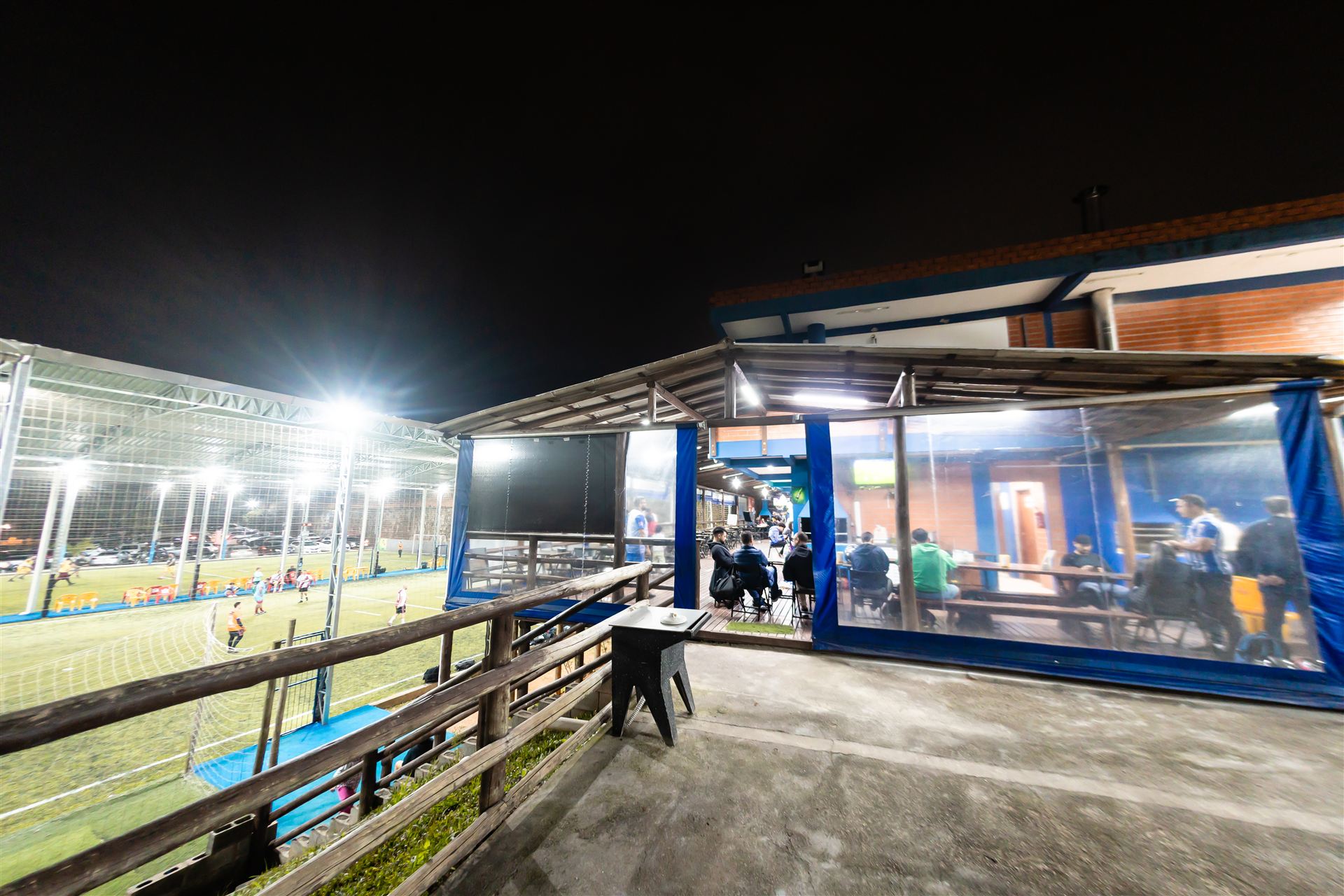 Deck varanda à noite com vista para a quadra society iluminada em São José SC